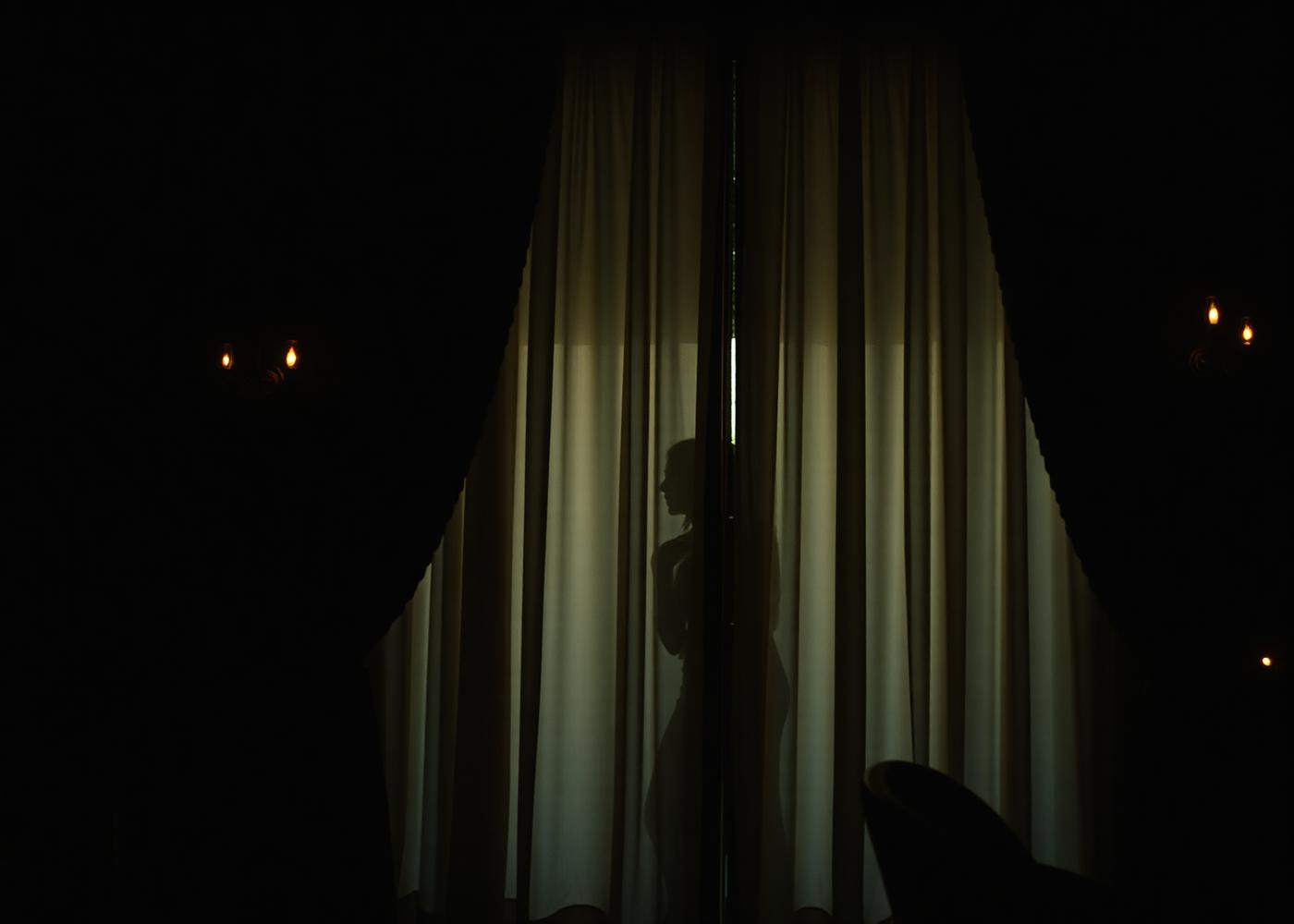 Candlelit silhouette behind a sheer curtain
